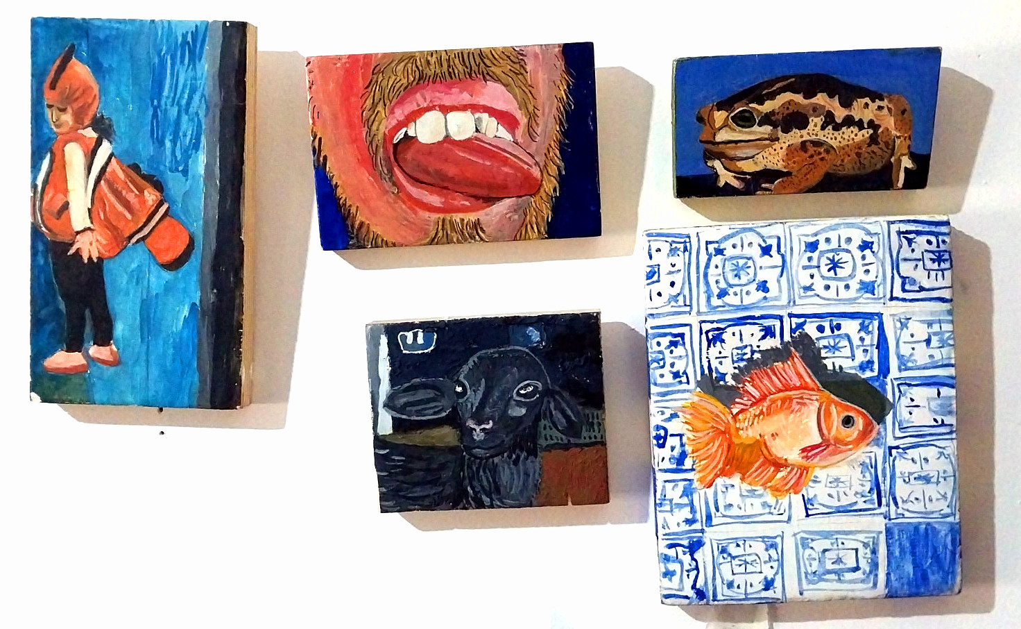Conjunto de pinturas finalizadas apoiadas contra a parede do ateliê